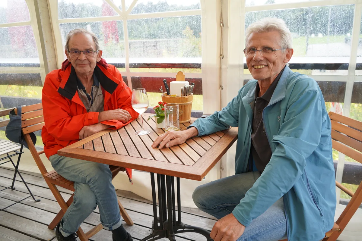 Zwei Rentner sitzen am Tisch und schauen zufrieden.